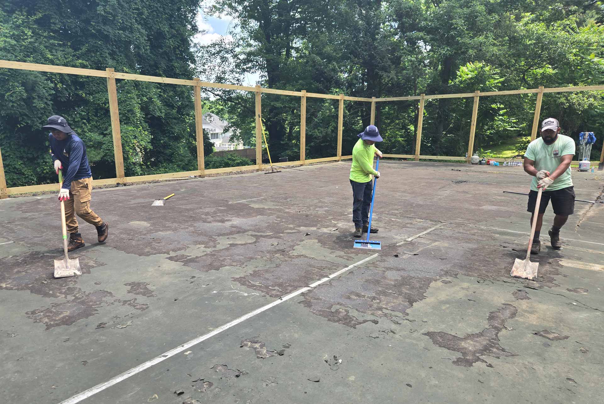 Workers from HOTMIXX LLC repairing a neglected tennis court